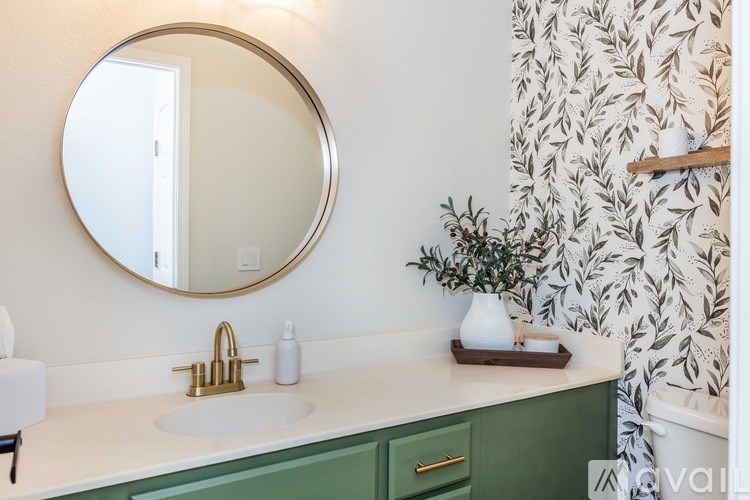 A bathroom with a green vanity and a round mirror.