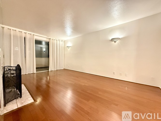 A spacious room with wooden flooring and white walls.