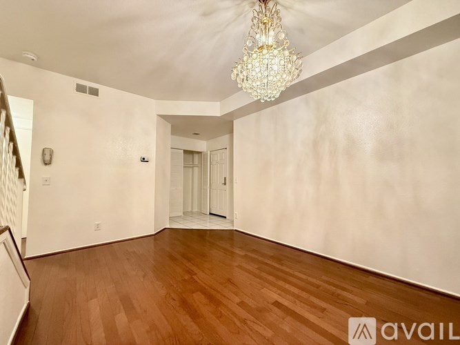 A room with wooden floors and a chandelier hanging from the ceiling.