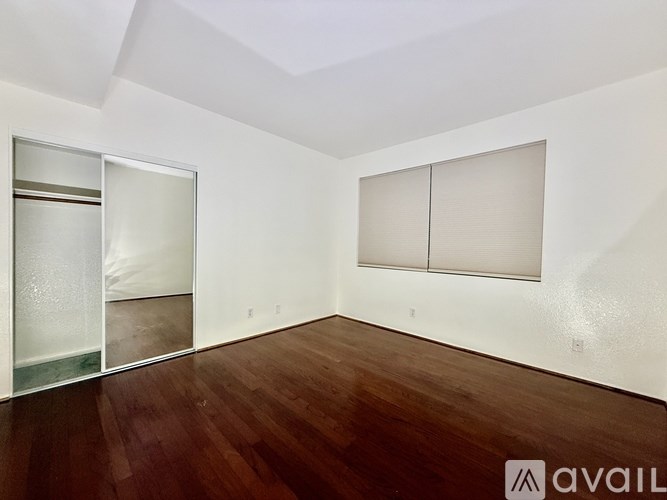A room with wooden floors and white walls has a sliding glass door and a white cabinet.