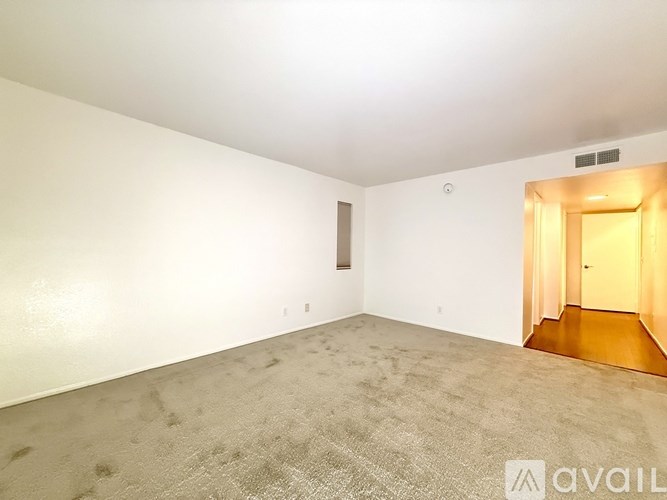 A spacious room with a carpeted floor and a doorway leading to another room.