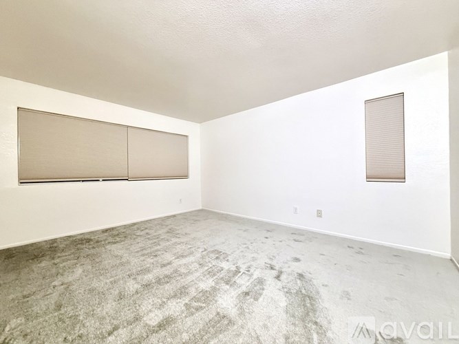 A room with a carpeted floor and a window with blinds.