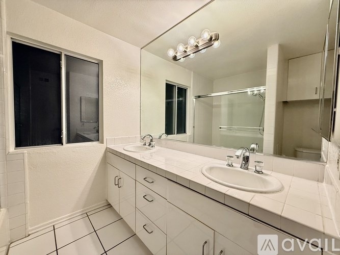 A white bathroom with a sink, mirror, and a window.
