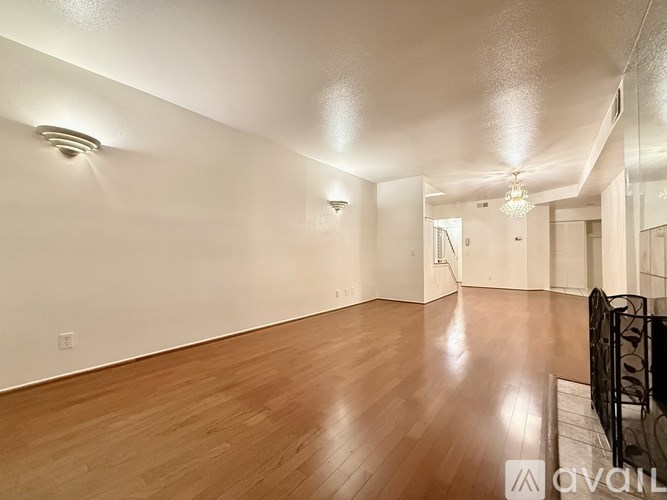 A spacious room with wooden flooring and white walls.