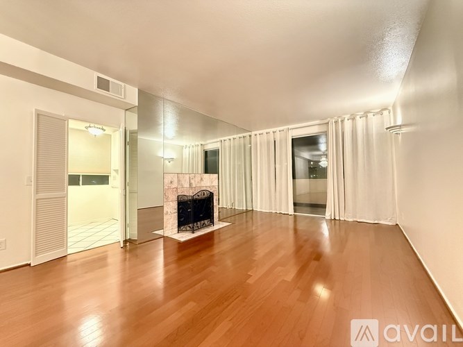 A spacious room with a fireplace and wooden flooring.