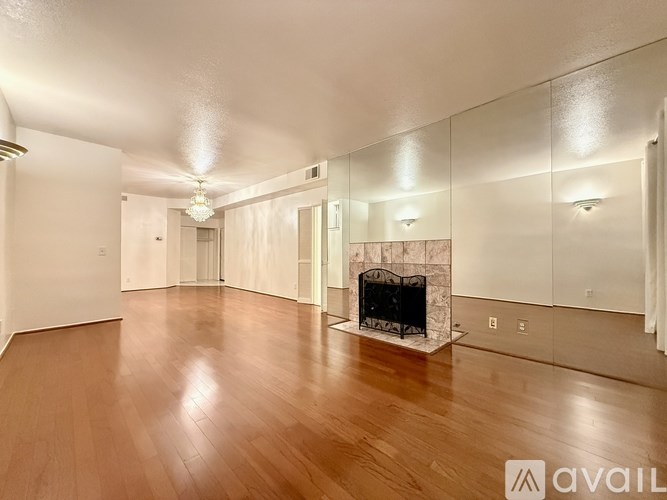 A spacious room with a fireplace and wooden floors.