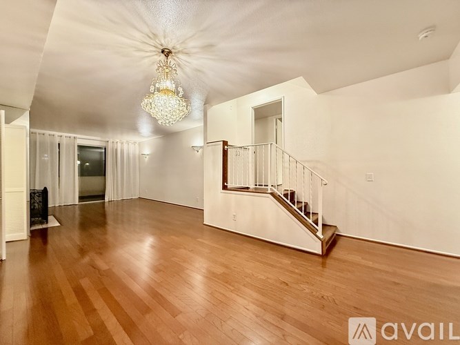 A large, empty room with wooden floors and a chandelier.