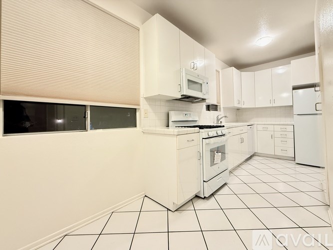 A white kitchen with a stove, microwave, and oven.