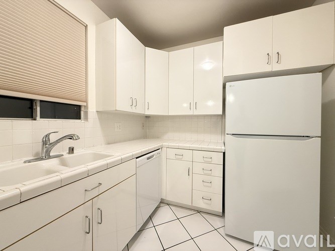 A kitchen with white cabinets and a white refrigerator.
