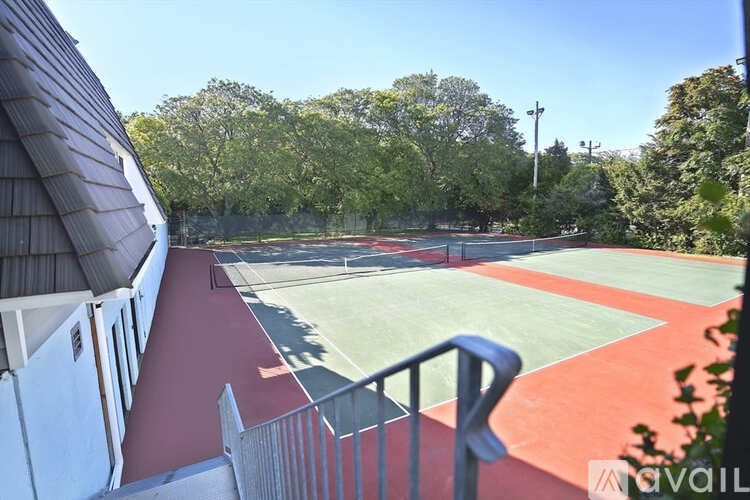 A tennis court is surrounded by trees and a building.