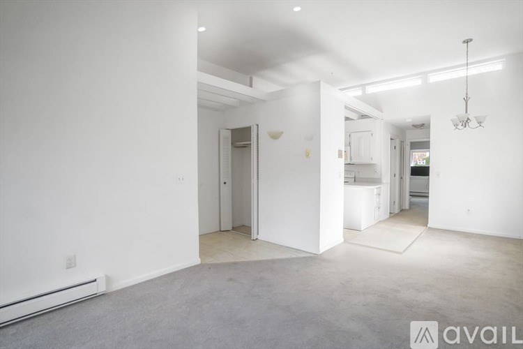 A spacious, empty room with a chandelier and a view into another room.
