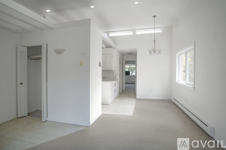 A spacious, empty room with white walls and a chandelier hanging from the ceiling.