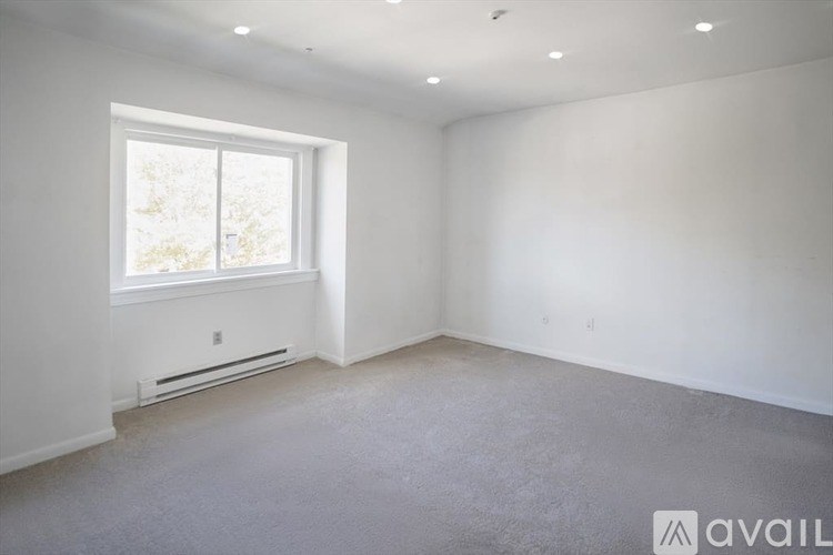 A spacious room with a window and a wall-mounted air conditioner.