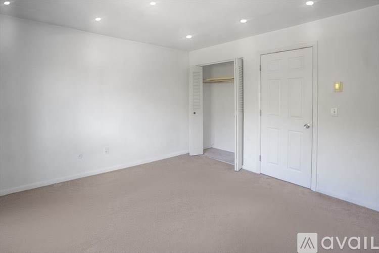 A room with white walls and a carpeted floor with a door on the right.