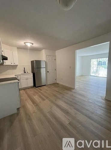A kitchen with white cabinets and a wooden floor.