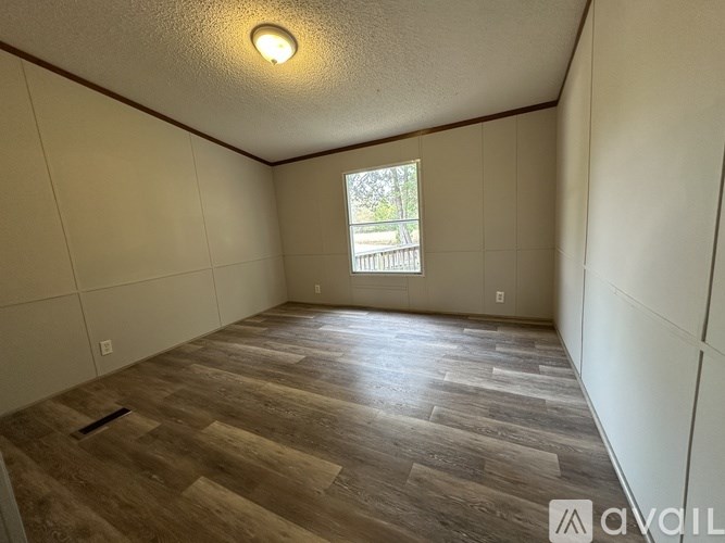 A room with wooden flooring and a window.