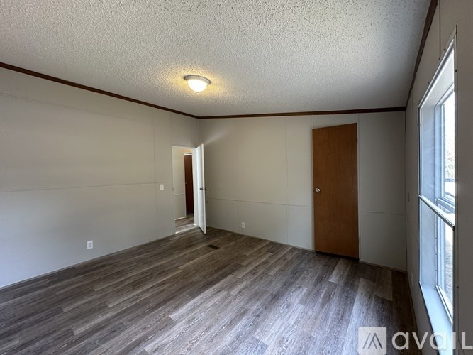 A room with wooden flooring and a door in the middle.