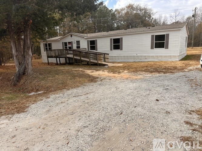 A mobile home with a deck and a gravel driveway.