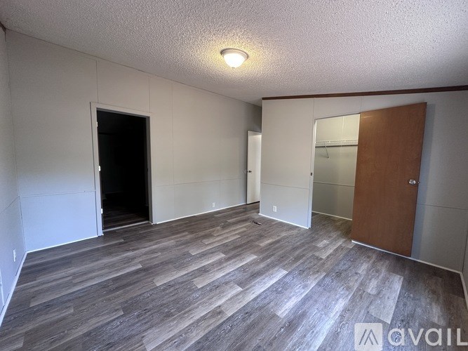 A room with a wooden floor and a door on the right side.
