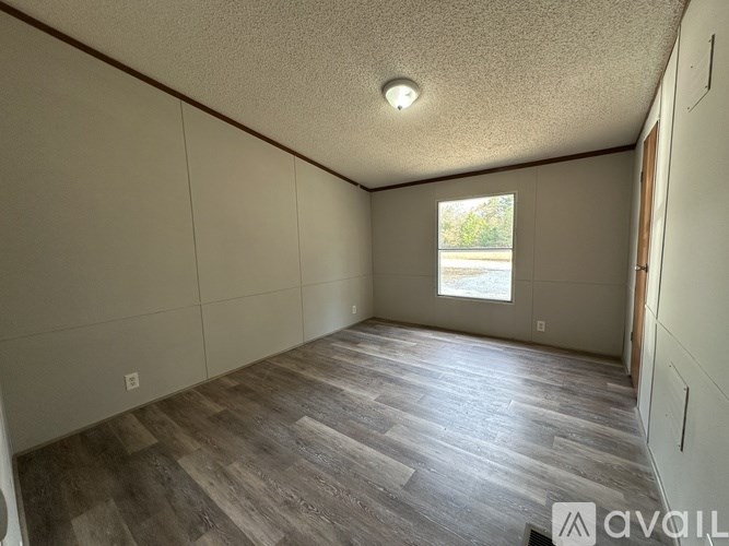 A room with wooden flooring and a window letting in natural light.