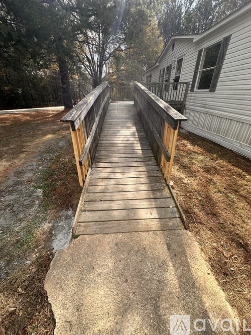 A wooden walkway leads to a white house.