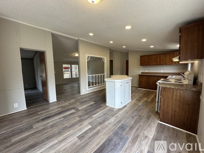 A spacious room with wood flooring and a kitchen area with brown cabinets.