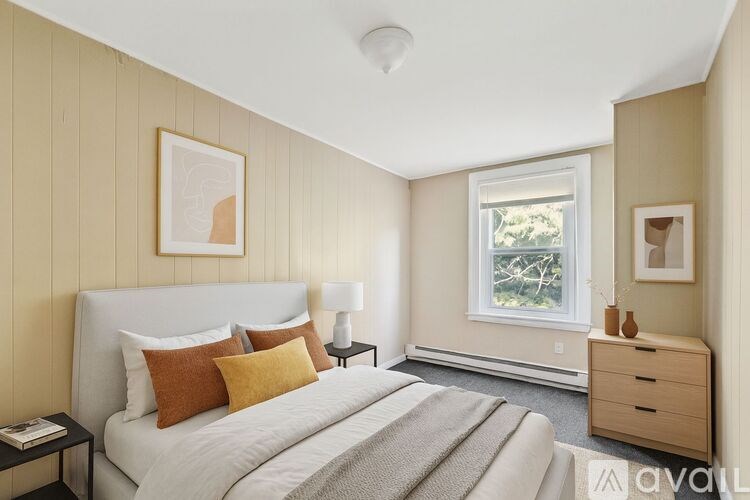 A bedroom with a bed, nightstand, and window.