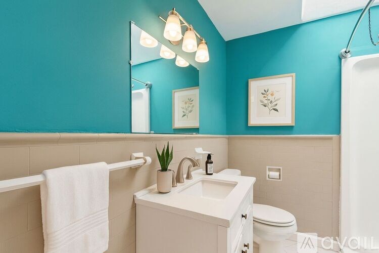 A white towel hangs on a towel rack in a blue-walled bathroom.