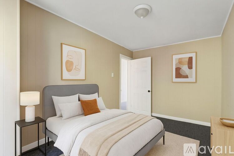 A bedroom with a bed, nightstand, and two framed pictures on the wall.