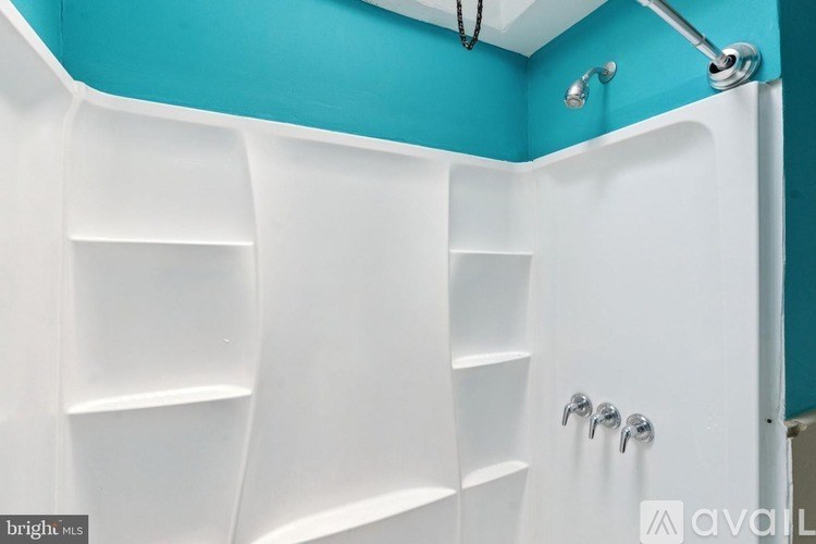 A white shower with a blue wall behind it.