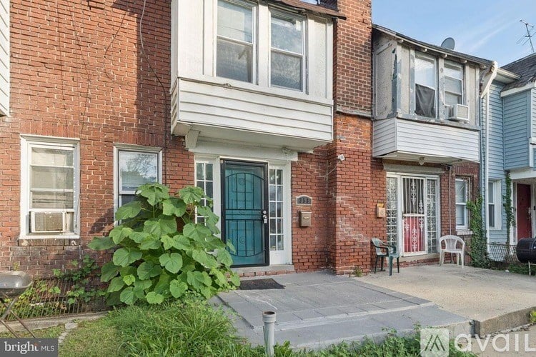 A red brick house with a green door and a white window.