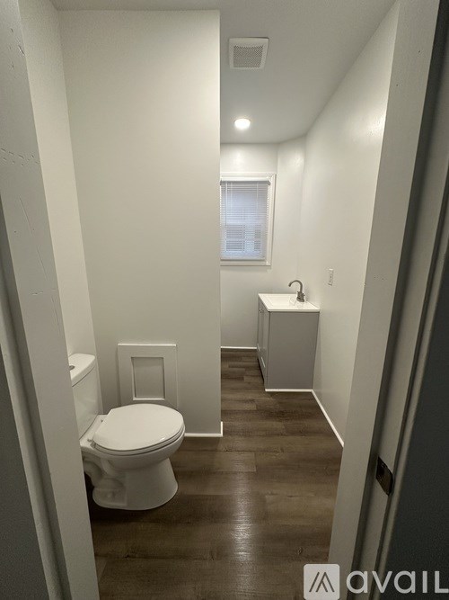 A small white toilet in a narrow hallway.