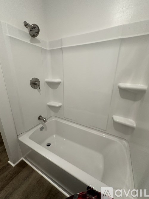 A white bathtub with a shower head and hand held shower.
