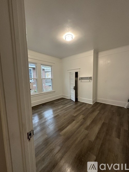 A room with wooden flooring and a door leading to another room.