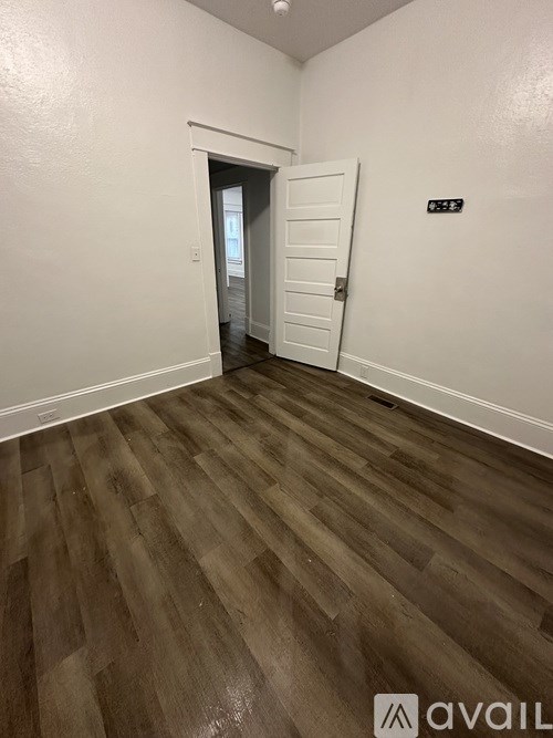 A room with wooden flooring and a white door.