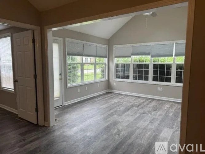 A room with a slanted ceiling, a door, and a window with blinds.