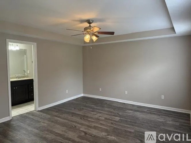 A room with a ceiling fan and wooden flooring.