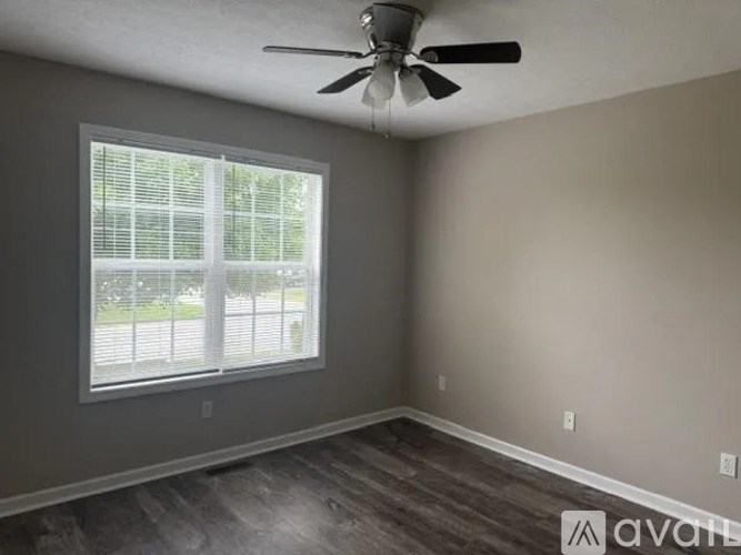 A room with a ceiling fan and a window with blinds.