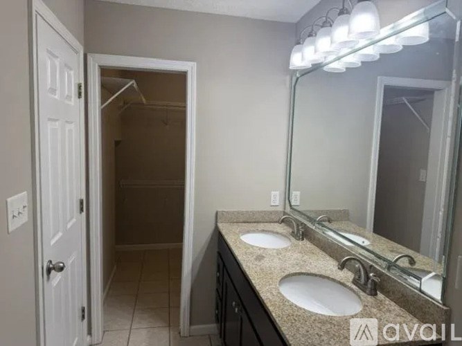 A bathroom with a sink, mirror, and lighting fixture.