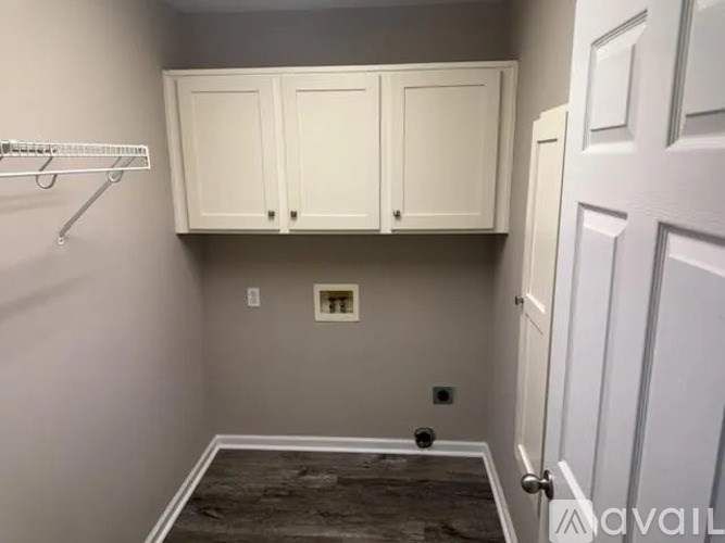 A small room with a white door, a shelf, and a cabinet.