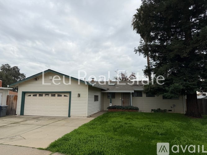 A house with a garage and a tree in front of it.