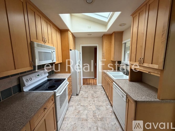 A kitchen with wooden cabinets and a skylight.