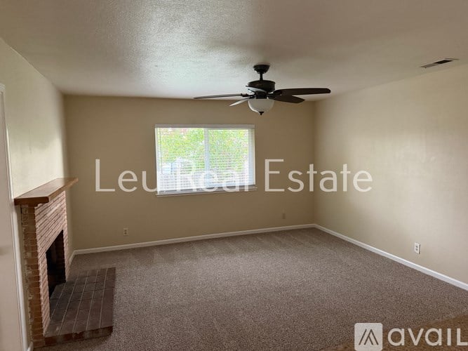 A living room with a fireplace and a ceiling fan.