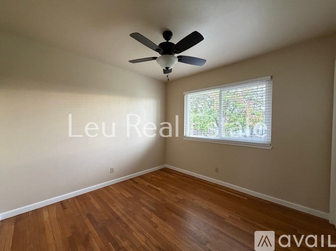 A room with a ceiling fan and a window with blinds.