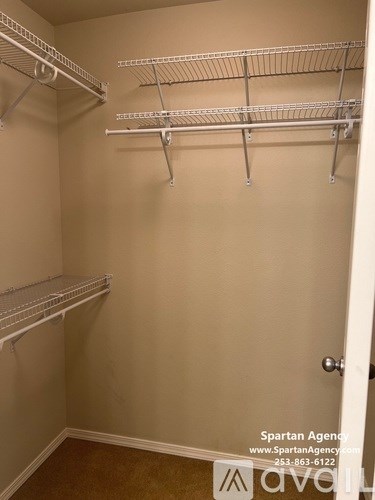 A walk-in closet with white shelving and a door on the right.