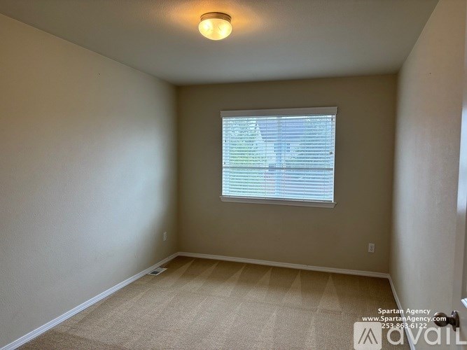 A room with a carpeted floor and a window with blinds.
