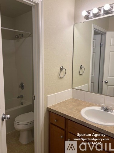 A bathroom with a toilet, sink, and mirror.
