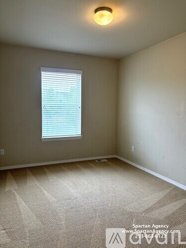 A room with a carpeted floor and a window with blinds.