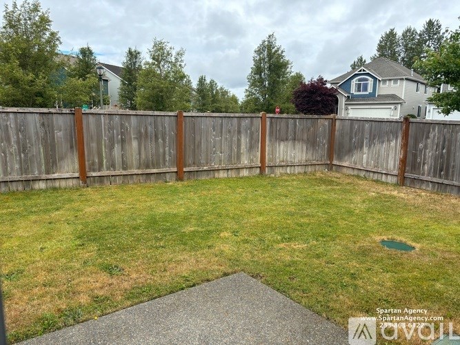 A backyard with a wooden fence and a green lawn.