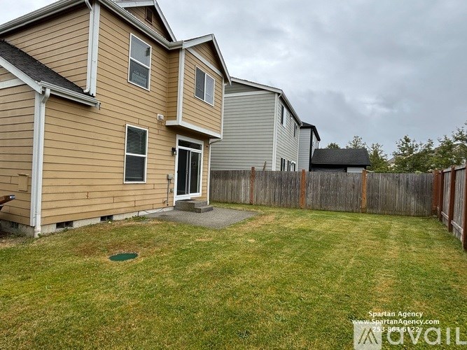 A house with a brown siding and a grey roof with a small front yard.